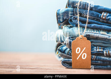 Vendita, sconto, Venerdì nero concetto con tag , jeans blu su sfondo chiaro. Copyspace. Foto Stock
