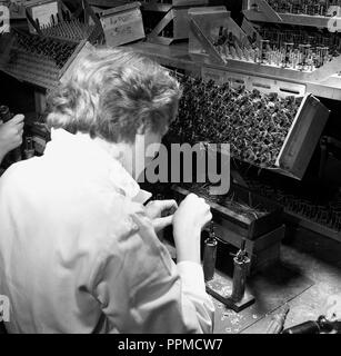 Degli anni Cinquanta, storico, un lavoratore di sesso femminile che seduti su un banco di lavoro a Bush Radio, un leader britannico produttore electonics del SER, la saldatura dei componenti o parti di radio. Foto Stock