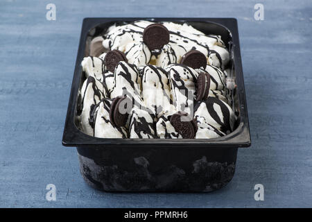 Appetitoso gelato in un contenitore di plastica su un decorativo sullo sfondo blu Foto Stock