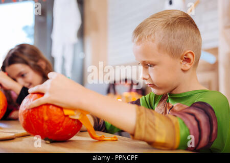 Ragazzo che indossa tartarughe Ninja costume sensazione divertirsi mentre la decorazione di zucca Foto Stock