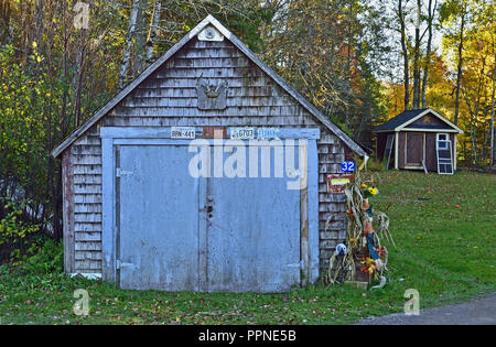 Un vecchio edificio con blue barn porte decorate con memorbilia e serve come un capannone per il rimessaggio nonché un garage Foto Stock