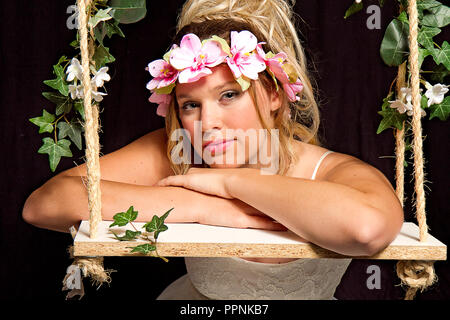 Parte bambina indossa ghirlanda di fiori sul suo capo in bianco Vestito chiffon isolati su sfondo nero Foto Stock