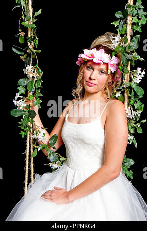 Parte bambina indossa ghirlanda di fiori sul suo capo in bianco Vestito chiffon isolati su sfondo nero Foto Stock