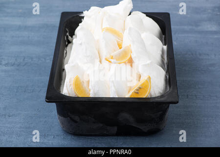 Appetitoso gelato in un contenitore di plastica su un decorativo sullo sfondo blu Foto Stock