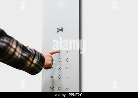 Close-up di una ragazza premendo un pulsante a sfioramento in un moderno ascensore. Foto Stock