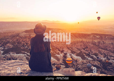 Una ragazza in un cappello sulla cima di una collina nel silenzio e nella solitudine si ammira il tranquillo paesaggio naturale e palloncini. Foto Stock
