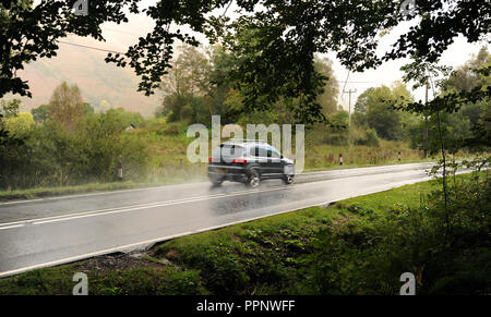 Automobile che viaggia vicino a Glencoe Scozia ri flette in strada la guida delle Highlands ubicazioni remote strade bagnate SCOTTISH REGNO UNITO Foto Stock