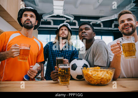 Concentrati gruppo multiculturale dei maschi di appassionati di calcio con birra guardando la partita di calcio al bar Foto Stock