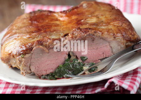 Sella di agnello farcito con funghi e spinaci su un piatto di portata Foto Stock