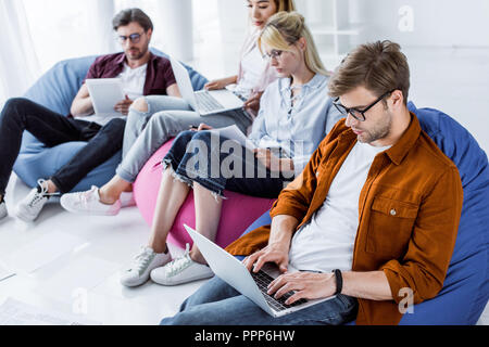 I colleghi multiculturale lavorando sul progetto di avvio con i notebook in ufficio Foto Stock