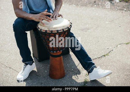 Vista ritagliata della African American uomo con djembe eseguendo sulla strada Foto Stock