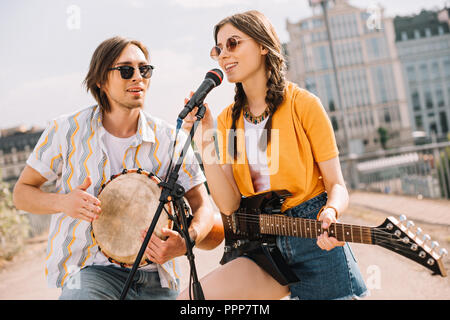 Maschi e femmine giovani con la chitarra e djembe eseguendo sulla strada Foto Stock