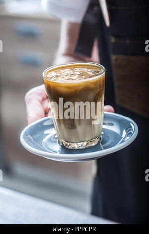 Barista in coffee shop tenendo in mano il bicchiere con ghiaccio caffè. Foto Stock