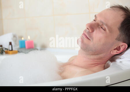 Uomo adulto avente una vasca da bagno con olio essenziale Foto Stock