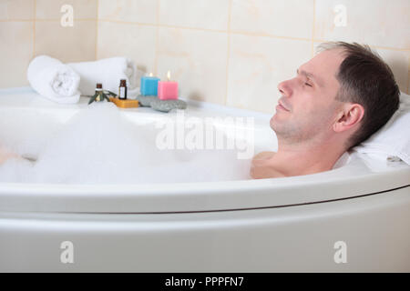 Uomo adulto avente una vasca da bagno con olio essenziale Foto Stock