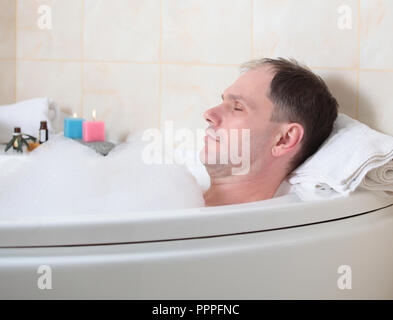 Uomo adulto avente una vasca da bagno con olio essenziale Foto Stock