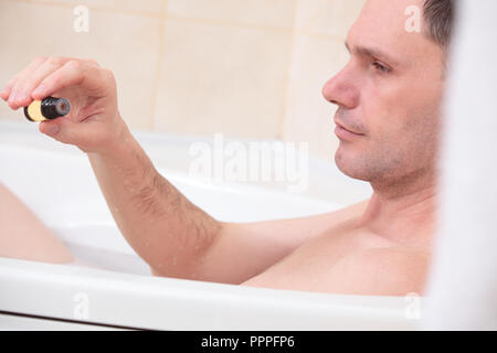 Uomo adulto avente una vasca da bagno con olio essenziale Foto Stock