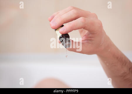 Uomo adulto avente una vasca da bagno con olio essenziale Foto Stock