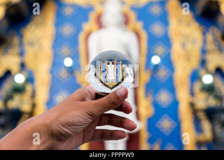 Il raccolto di mano azienda turistica sfera di vetro con upside riflessione di antico tempio in Thailandia Foto Stock