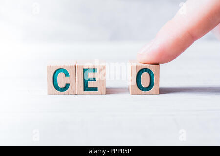 La sigla CEO formata da blocchi di legno e disposti da un maschio di dito su un tavolo bianco Foto Stock