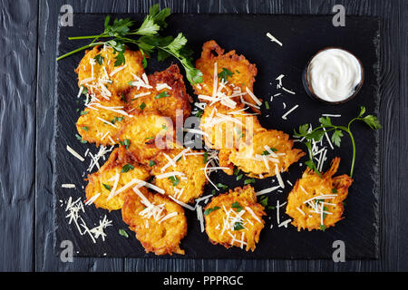 Vegetariano deliziose frittelle dolci di zucca e Parmigiano servito con panna acida o yogurt greco condito con prezzemolo fresco su un Foto Stock