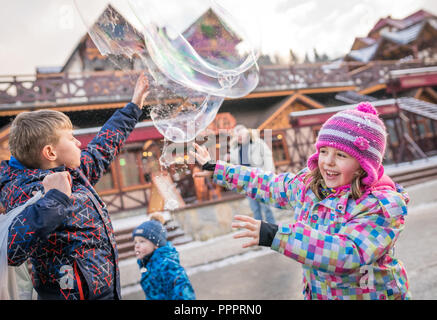 Karpacz, Polonia - Febbraio 2018 : bambini che cercano di gigante cattura bolle di sapone sulla strada principale che porta in città Karpacz, polacco inverno ski resort Foto Stock