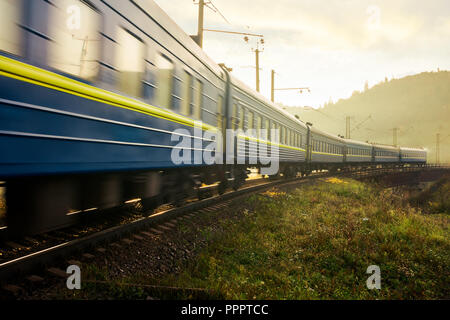 Un rapido movimento del treno attraverso il viadotto in montagna. vecchio concetto di trasporto. deliziosa campagna di sunrise Foto Stock