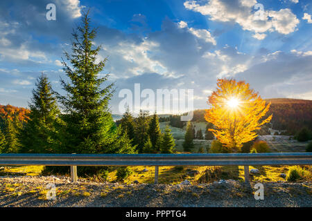 Splendida mornig in montagna. raggi di sole venuto attraverso la struttura Corona in golden fogliame. bellissimo paesaggio autunnale con bel cielo Foto Stock