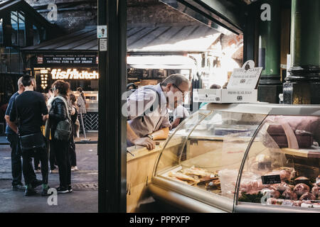 London, Regno Unito - 24 Luglio 2018: cliente sta guardando i formaggi presso gli stand di Borough Market, uno dei più grandi e più antiche i mercati alimentari a Londra. Foto Stock