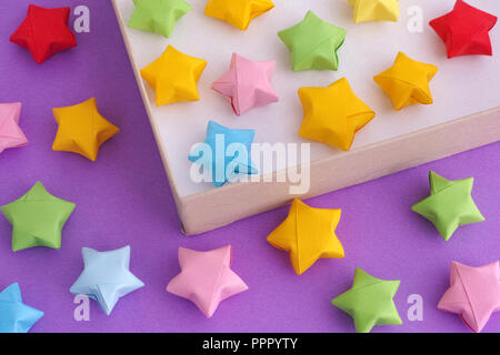 Origami colorati lucky stelle in una scatola di carta. Close up. Foto Stock