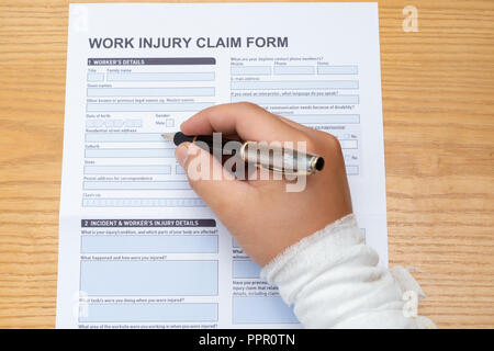 Il riempimento di un pregiudizio di lavoro modulo di rivendicazione con una mano avvolto di medico e di concetto di assicurazione Foto Stock