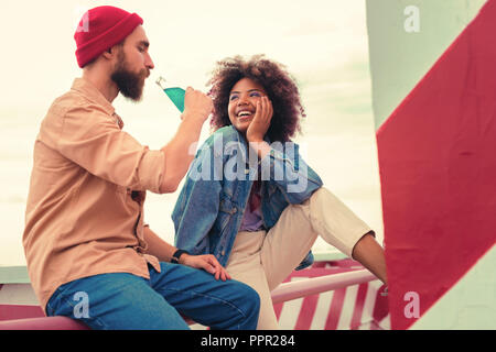 Giovane uomo di bere dalla bottiglia e ragazza guardando lui Foto Stock