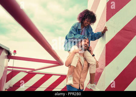 Felice giovane uomo ridere mentre si sta portando la sua fidanzata sulle spalle Foto Stock