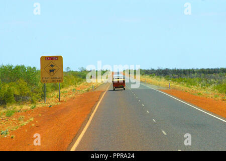 VEICOLO SULLA STRADA DELL'OUTBACK DELL'AUSTRALIA OCCIDENTALE PASSANTE UN SEGNALE STRADALE DI ATTENZIONE CHE INDICA CHE GLI ANIMALI POSSONO ATTRAVERSARE NEI PROSSIMI 280 KM. Foto Stock