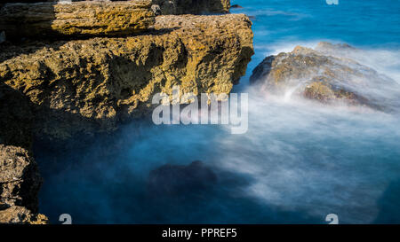 Le onde del mare sono a battere contro la costa rocciosa Foto Stock