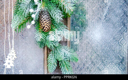 Naturale Natale Capodanno giocattolo cono di pino e albero di Natale ramo di close-up. Nevicata, caduta di fiocchi di neve, macchie di colore bianco. Inverno Natale Anno nuovo sfondo. Foto Stock