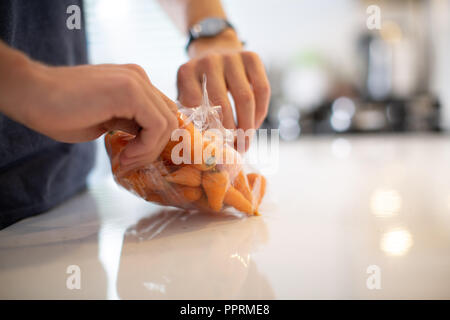 Disimballaggio avvolte in plastica la frutta e la verdura in cucina - Imballaggi di plastica su frutta e verdura NEL REGNO UNITO Foto Stock