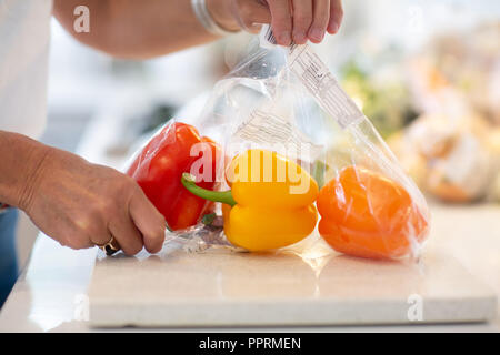 Disimballaggio avvolte in plastica la frutta e la verdura in cucina - Imballaggi di plastica su frutta e verdura NEL REGNO UNITO Foto Stock