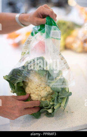 Disimballaggio avvolte in plastica la frutta e la verdura in cucina - Imballaggi di plastica su frutta e verdura NEL REGNO UNITO Foto Stock