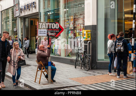 L'uomo azienda tattoo shop segno su Oliver Plunkett Street, Cork, Irlanda. Foto Stock