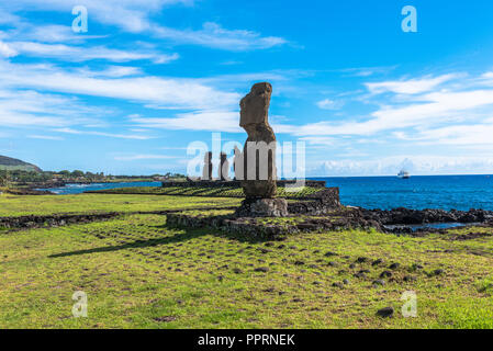 Una fila di Moai statue sulla costa guardando verso l'interno sull'Isola di Pasqua. sotto un luminoso cielo blu. Foto Stock