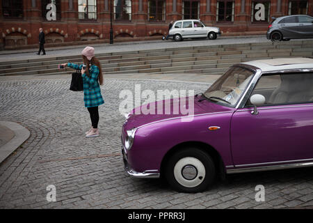 Ragazza tenendo un selfie nella parte anteriore di un Nissan Figaro. Foto Stock