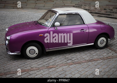 Viola Nissan Figaro parcheggiato sul ciottolato. Foto Stock