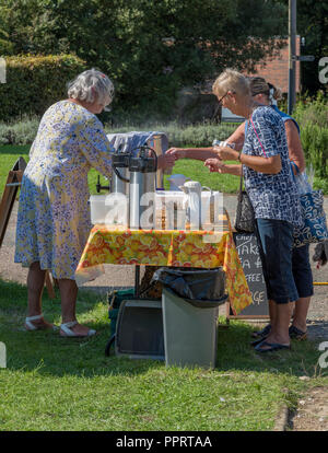 Più anziani o persone di mezza età casalinghe che serve il tè e i biscotti in un paese di campagna fete o fiera. Womens gilde o istituti. Foto Stock