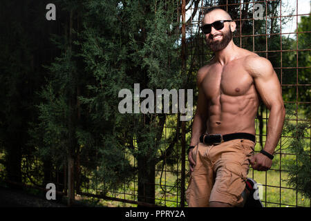 Ritratto di un giovane fisicamente l uomo che mostra il suo ben addestrato corpo - Atletico muscolare Bodybuilder Modello di Fitness in posa all'aperto - un posto per il vostro Foto Stock