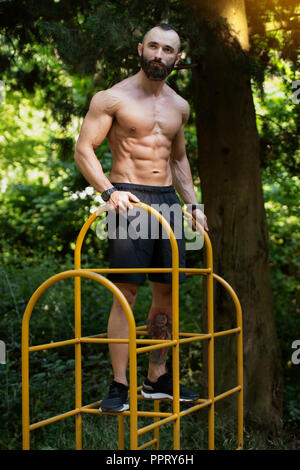 Ritratto di un giovane fisicamente l uomo che mostra il suo ben addestrato corpo - Atletico muscolare Bodybuilder Modello di Fitness in posa all'aperto - un posto per il vostro Foto Stock