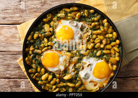 Iraniano Ghatogh Baghali stufato di fagioli e aneto con uova fritte, aglio e curcuma close-up in una padella su una tavola orizzontale vista superiore da abov Foto Stock