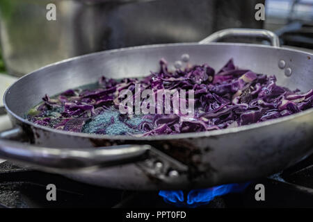 I rifugiati politici sfuggiti dall Africa a bordo di una barca. Trovato accoglienza e lavoro in Europa. Ristorante vegano, cuoco partecipante, acciaio pentolame e stoviglie, il bruciatore a gas. Foto Stock