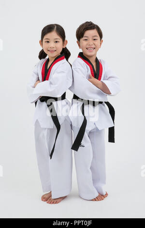 Bambini all'istruzione. Taekwondo, piccolo ragazzo e ragazza pratica le arti marziali in sfondo bianco 239 Foto Stock