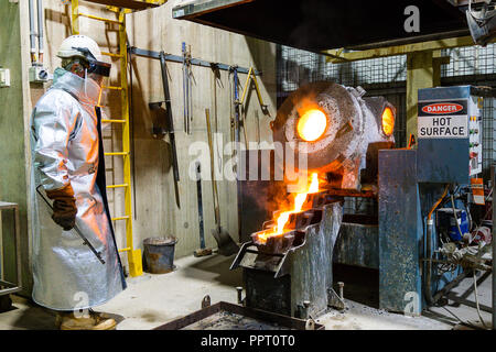 Lavoratore in abbigliamento protettivo versando in oro dal forno ad una miniera d'Oro in Australia Occidentale Foto Stock